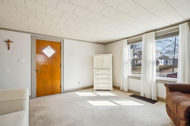 living area with crown molding, light colored carpet, visible vents, and baseboards