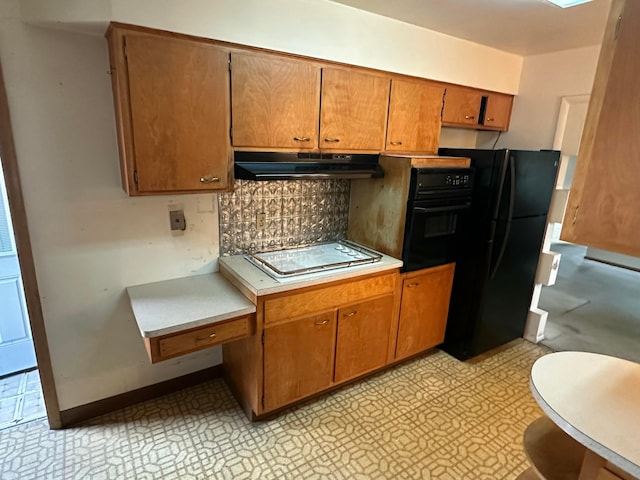 kitchen with brown cabinets, black appliances, under cabinet range hood, light countertops, and light floors