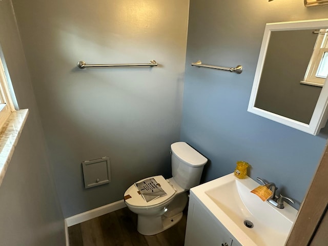 bathroom with baseboards, toilet, wood finished floors, and vanity