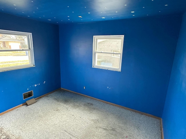 carpeted spare room with visible vents and baseboards