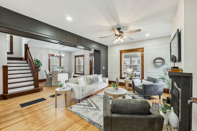 living area featuring a decorative wall, light wood-style flooring, stairs, and visible vents