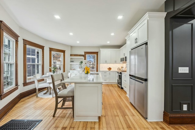 kitchen featuring light wood-type flooring, stainless steel appliances, white cabinetry, and light countertops