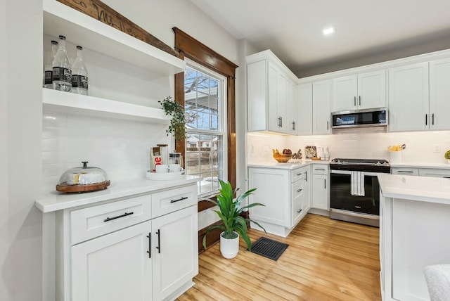 kitchen featuring white cabinetry, open shelves, light wood-style floors, and appliances with stainless steel finishes