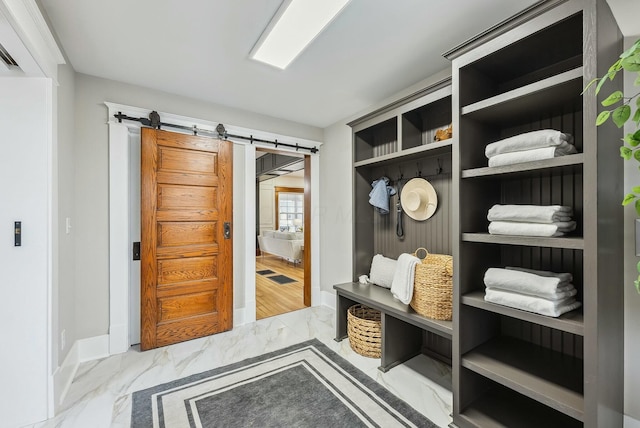 mudroom featuring a barn door, baseboards, and marble finish floor