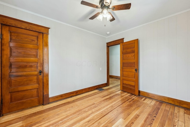 spare room with crown molding, baseboards, light wood finished floors, and ceiling fan