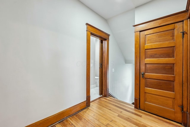 interior space with light wood-type flooring, baseboards, and vaulted ceiling