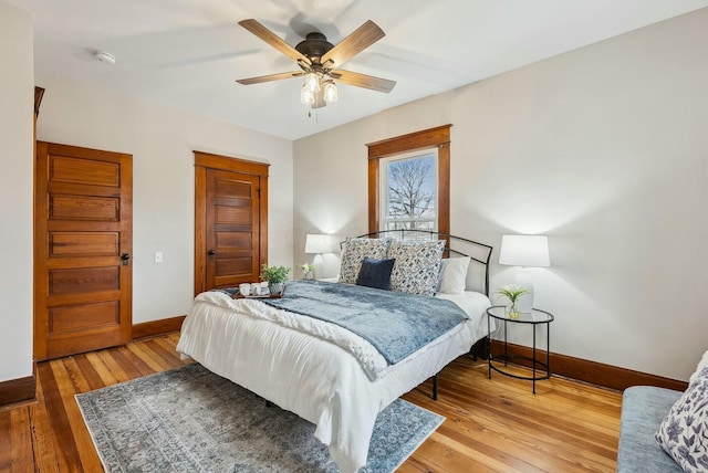 bedroom with light wood-style flooring, a ceiling fan, and baseboards