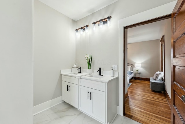 ensuite bathroom with marble finish floor, ensuite bathroom, baseboards, and a sink