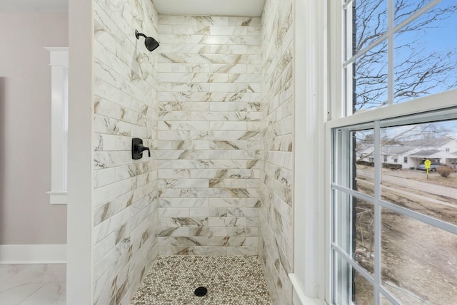 bathroom featuring marble finish floor and a tile shower