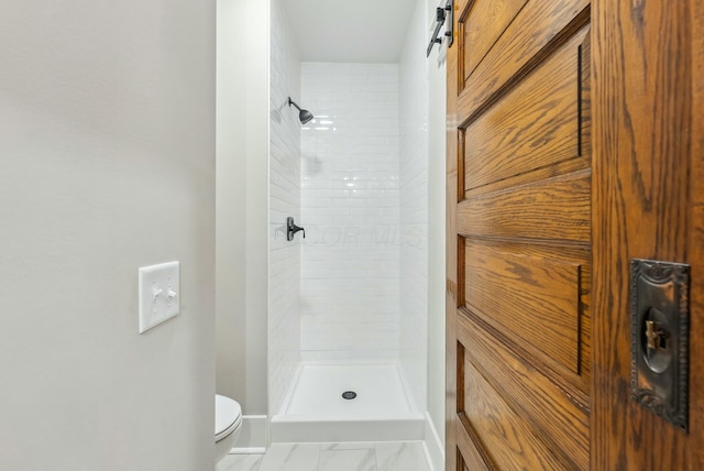 bathroom featuring a shower stall, toilet, marble finish floor, and baseboards