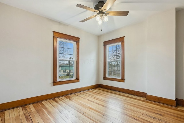 spare room featuring hardwood / wood-style flooring, a ceiling fan, and baseboards