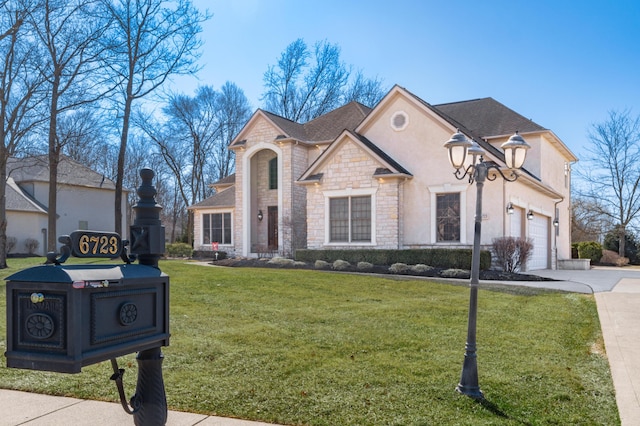 french country style house with stucco siding, stone siding, concrete driveway, a front yard, and a garage