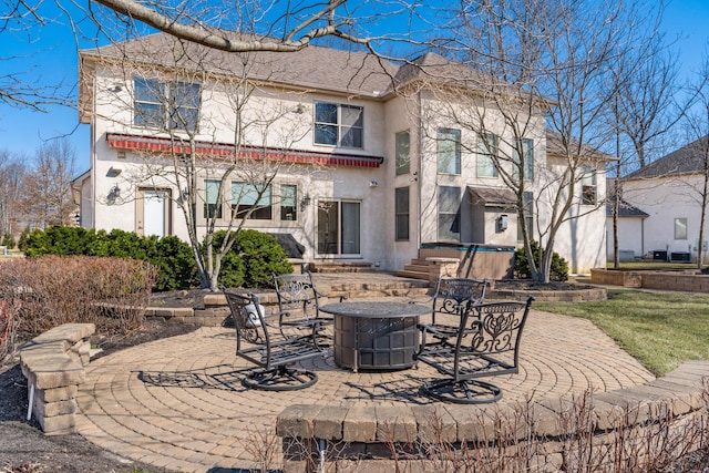 back of property featuring a patio area, stucco siding, and a fire pit