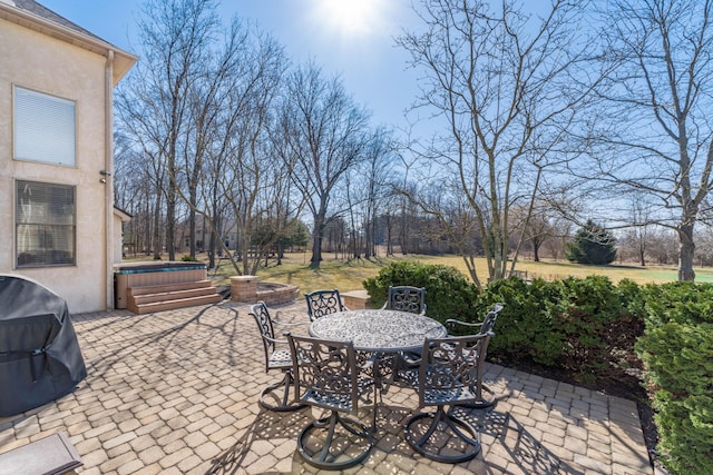 view of patio / terrace with outdoor dining area, a hot tub, and a grill