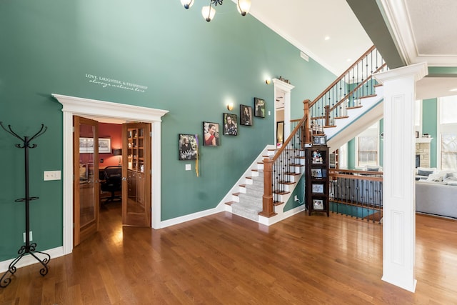 stairs featuring crown molding, wood finished floors, baseboards, and a towering ceiling