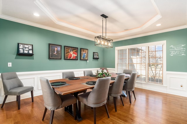 dining area featuring a tray ceiling, wainscoting, wood finished floors, and crown molding