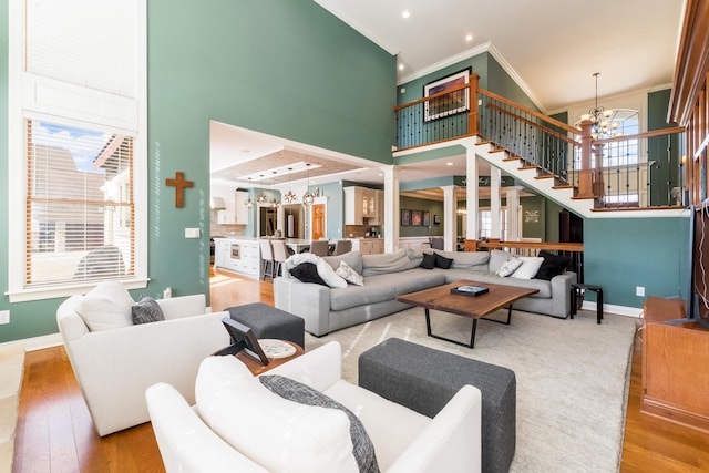 living room featuring a notable chandelier, wood finished floors, baseboards, and a towering ceiling