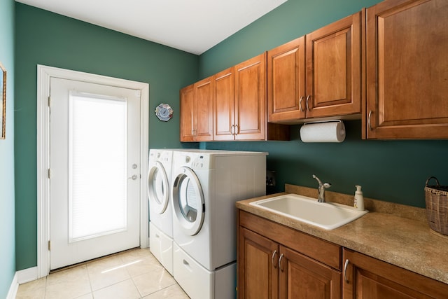 clothes washing area featuring a sink, cabinet space, light tile patterned floors, and washer and clothes dryer