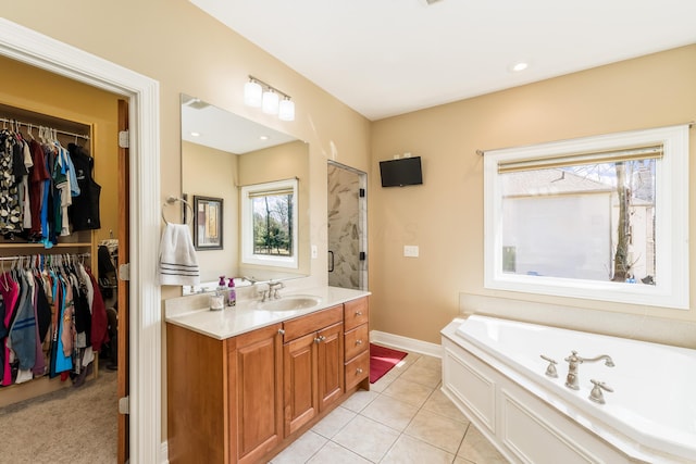 bathroom with tile patterned flooring, baseboards, a spacious closet, a bath, and vanity