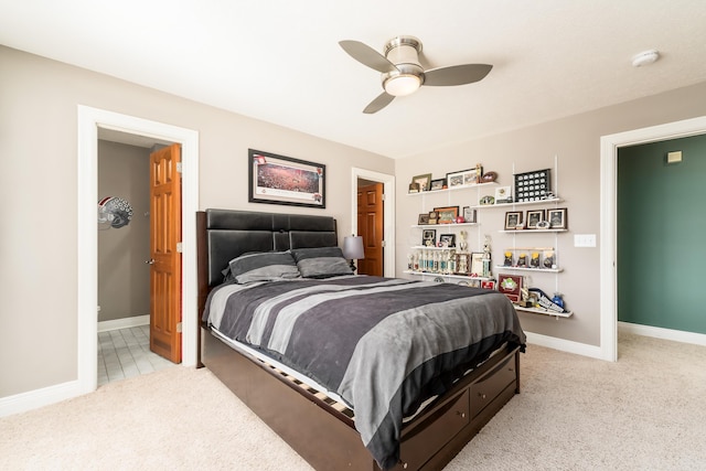 bedroom featuring light carpet, ceiling fan, ensuite bath, and baseboards