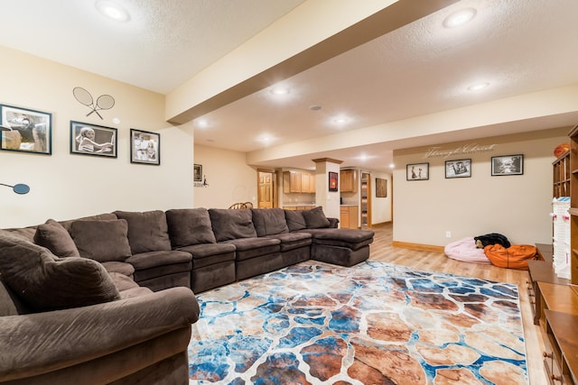 living area featuring recessed lighting, light wood-type flooring, baseboards, and a textured ceiling