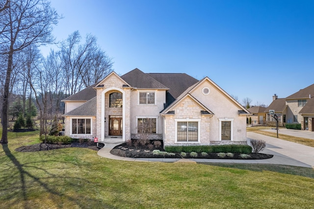 french country inspired facade with stone siding, stucco siding, a shingled roof, and a front lawn