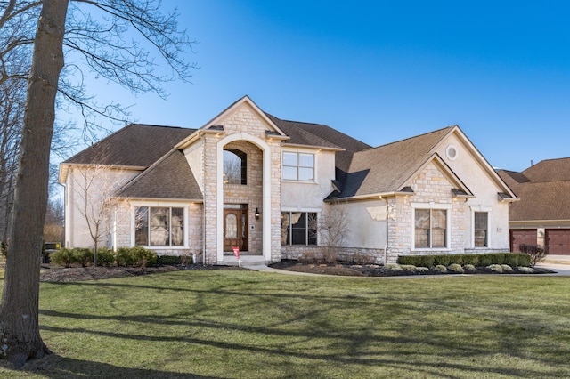 french country home with a front yard, stone siding, roof with shingles, and stucco siding