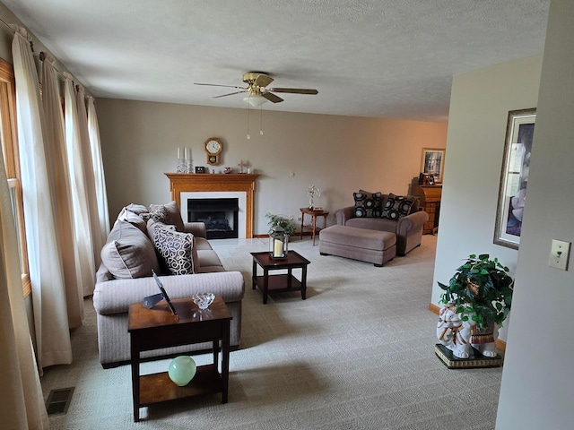 living room with visible vents, light carpet, a ceiling fan, a textured ceiling, and a fireplace