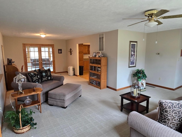 living area with light carpet, a textured ceiling, french doors, baseboards, and ceiling fan