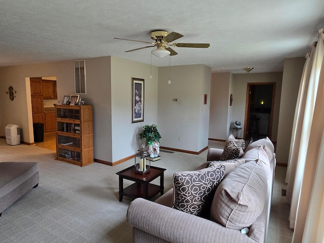 living room with a textured ceiling, ceiling fan, baseboards, and light carpet