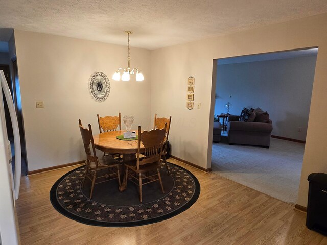 dining room with baseboards, a textured ceiling, an inviting chandelier, and wood finished floors