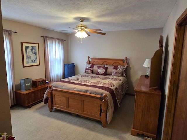 bedroom with a ceiling fan, light colored carpet, and a textured ceiling