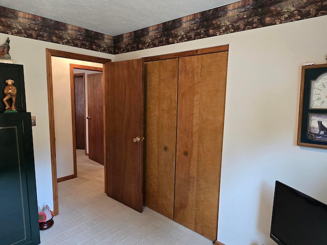 bedroom with light carpet, baseboards, a closet, and a textured ceiling