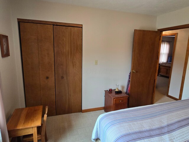 bedroom with light colored carpet, baseboards, and a closet