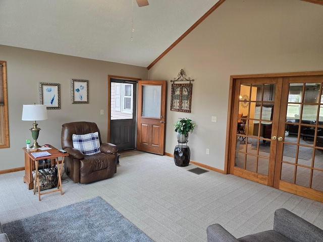 carpeted living area with baseboards, visible vents, french doors, and high vaulted ceiling