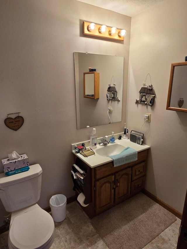 bathroom with vanity, toilet, baseboards, and tile patterned flooring