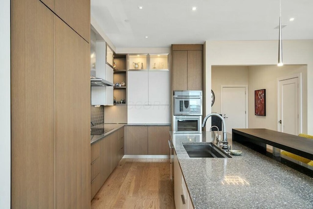 kitchen featuring modern cabinets, a sink, open shelves, light wood-style floors, and black electric cooktop