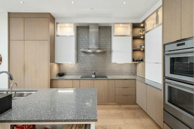 kitchen with stainless steel double oven, open shelves, a sink, wall chimney exhaust hood, and black electric cooktop