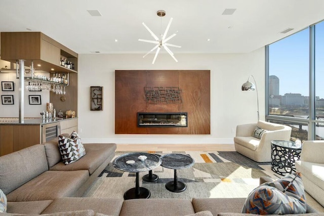 living area featuring visible vents, beverage cooler, a glass covered fireplace, floor to ceiling windows, and bar