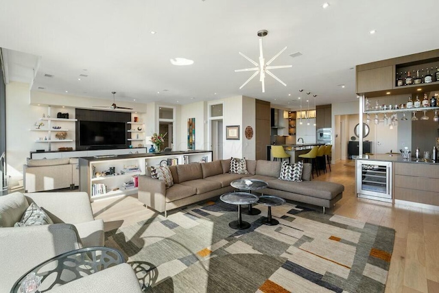 living area featuring light wood-type flooring, indoor wet bar, beverage cooler, and recessed lighting