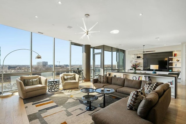 living room featuring a wall of windows, visible vents, wood finished floors, and ceiling fan