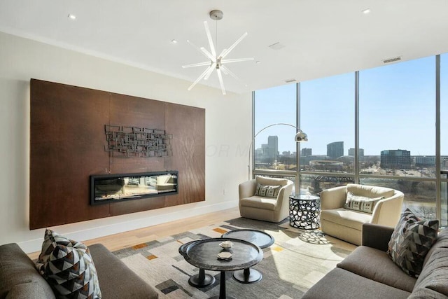 living room with wood finished floors, visible vents, expansive windows, a glass covered fireplace, and a view of city