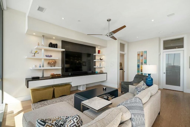 living room featuring visible vents, baseboards, wood finished floors, and a ceiling fan