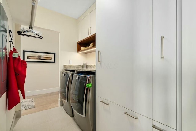 laundry area featuring bar area, cabinet space, light tile patterned floors, baseboards, and washing machine and clothes dryer