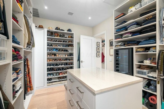 walk in closet with beverage cooler, visible vents, and light wood-type flooring