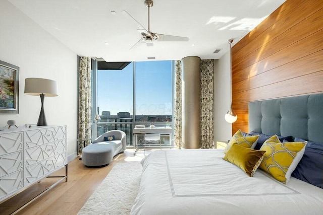 bedroom featuring wood walls, a wall of windows, ceiling fan, and wood finished floors