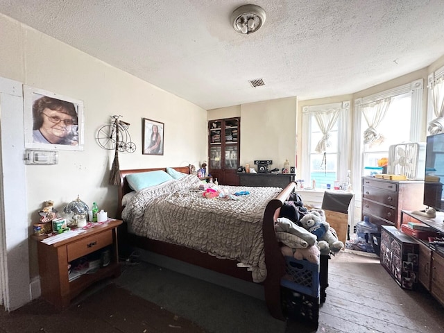 bedroom featuring visible vents, a textured ceiling, and hardwood / wood-style floors