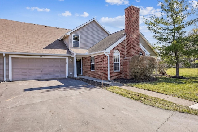 view of front of home with a front yard, driveway, an attached garage, a chimney, and brick siding