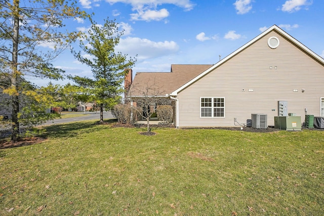 back of house with cooling unit, a lawn, and a chimney