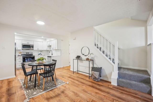 dining area featuring light wood finished floors, stairway, and baseboards